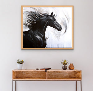 Black and white horse painting on a wall in a frame above a small wooden desk